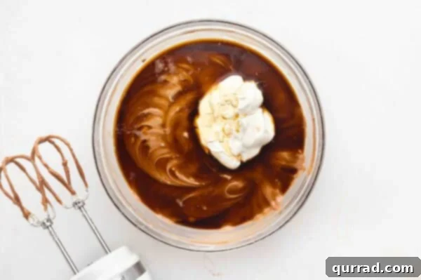 sour cream and coffee on top of whipped cream cheese in glass mixing bowl