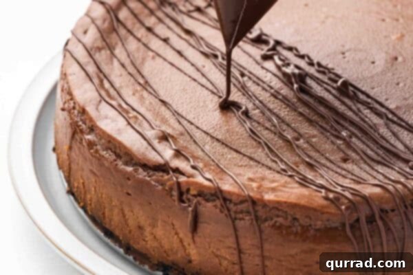 chocolate ganache being drizzled over uncut chocolate cheesecake