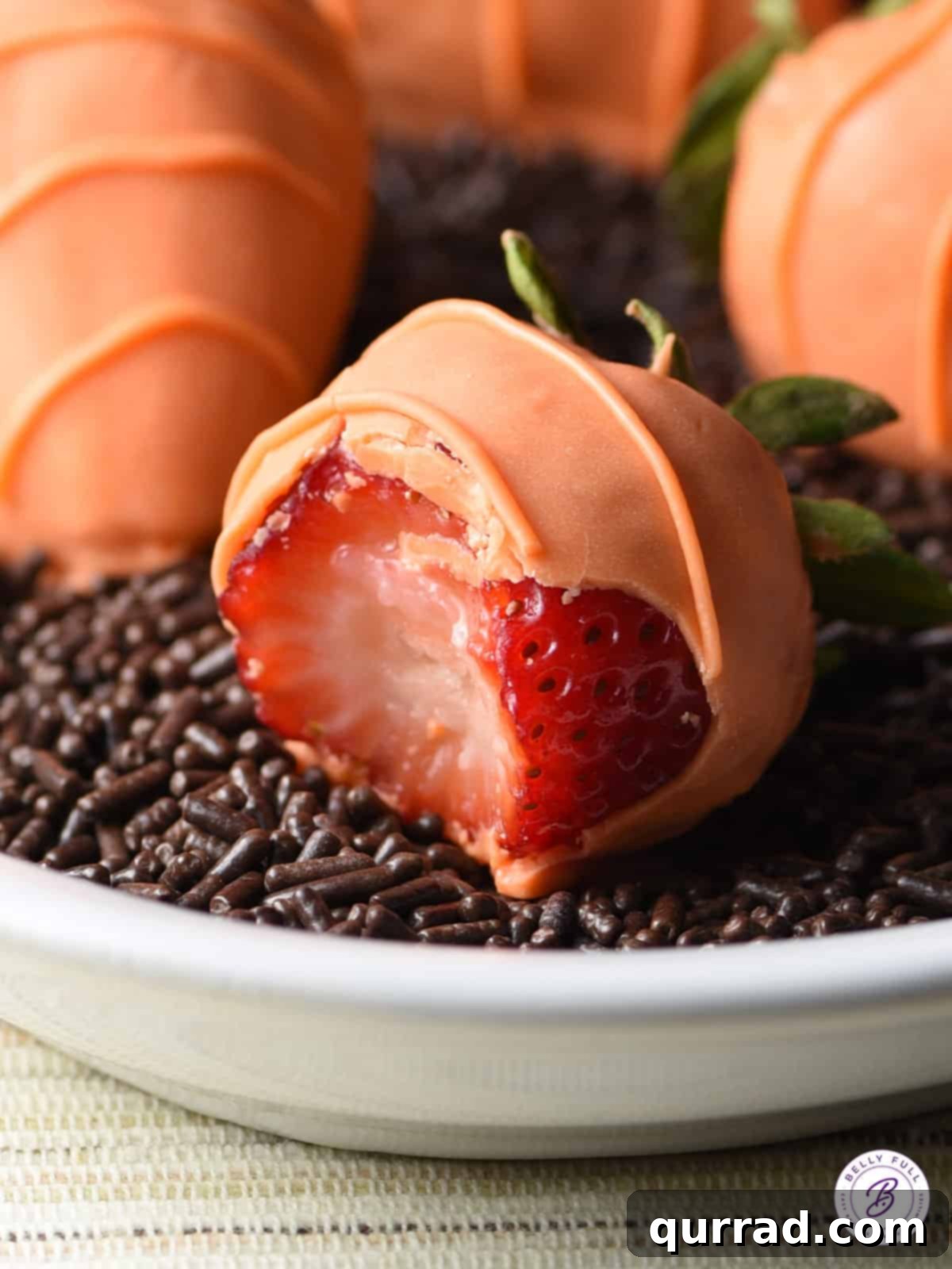 Achieve a smooth, even coating with ease by using quality orange candy melts and the right dipping technique for your strawberry carrots. A single strawberry being carefully dipped into a bowl of smooth orange candy melts