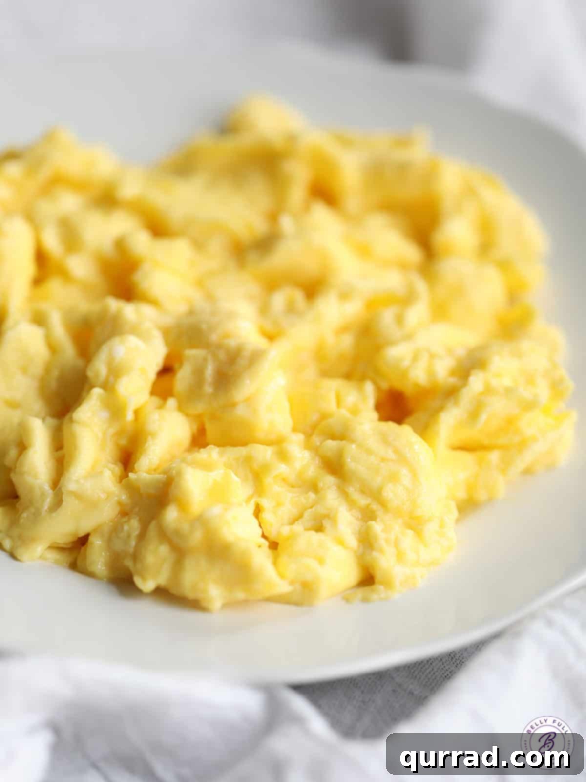 Unlock the Art of Perfect Scrambled Eggs 2 close up of fluffy scrambled eggs on plate, garnished with fresh herbs