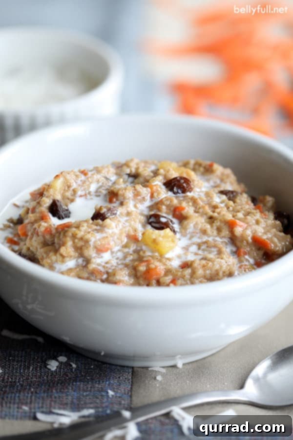 Close-up of creamy steel cut carrot cake oatmeal in a white bowl, garnished with toasted coconut and chopped nuts