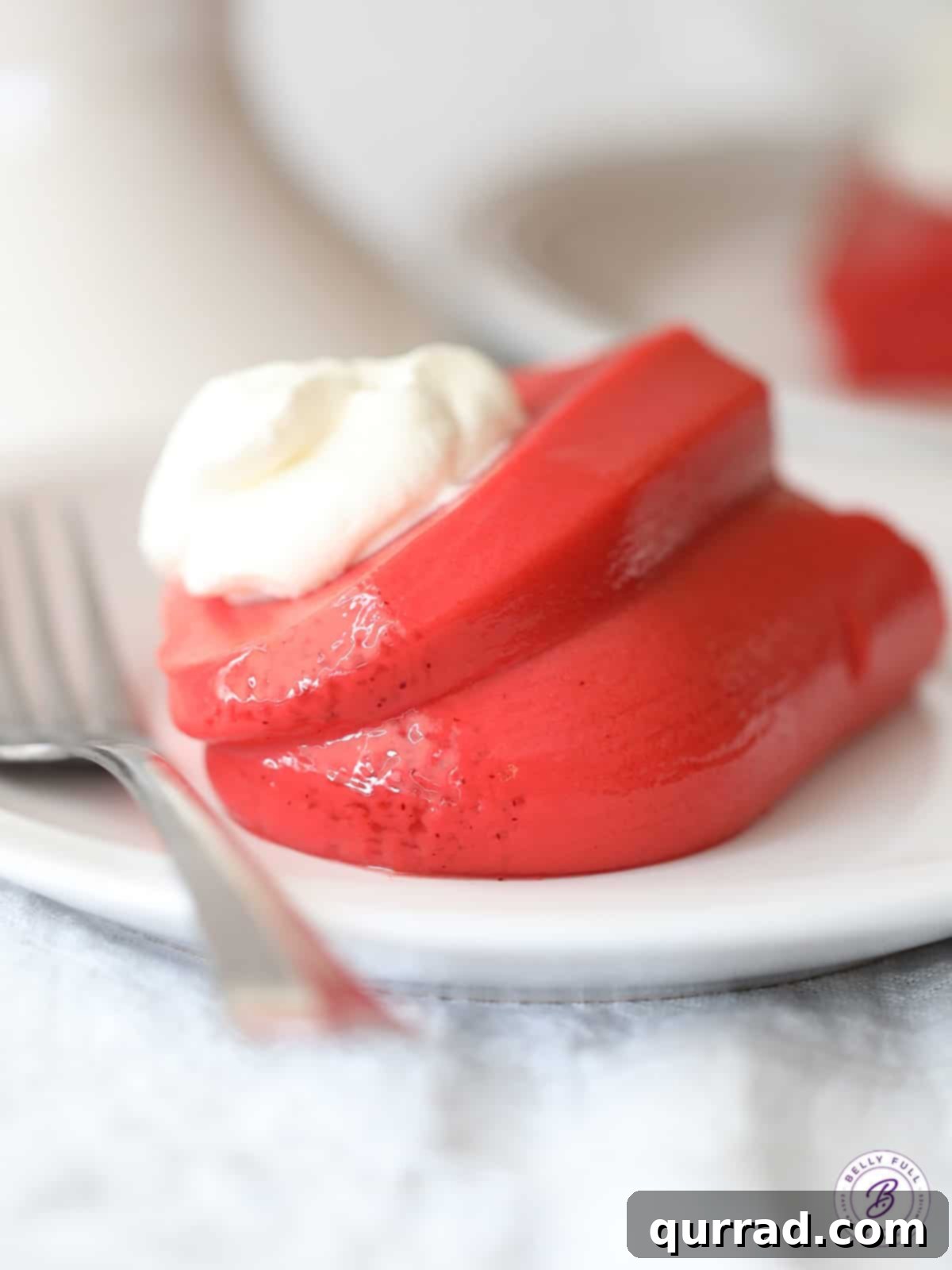 Velvety Strawberry Swirl Jello 4 A close-up shot of a sliced creamy strawberry jello mold on a plate, topped with a generous dollop of fluffy whipped cream, emphasizing its delectable texture.