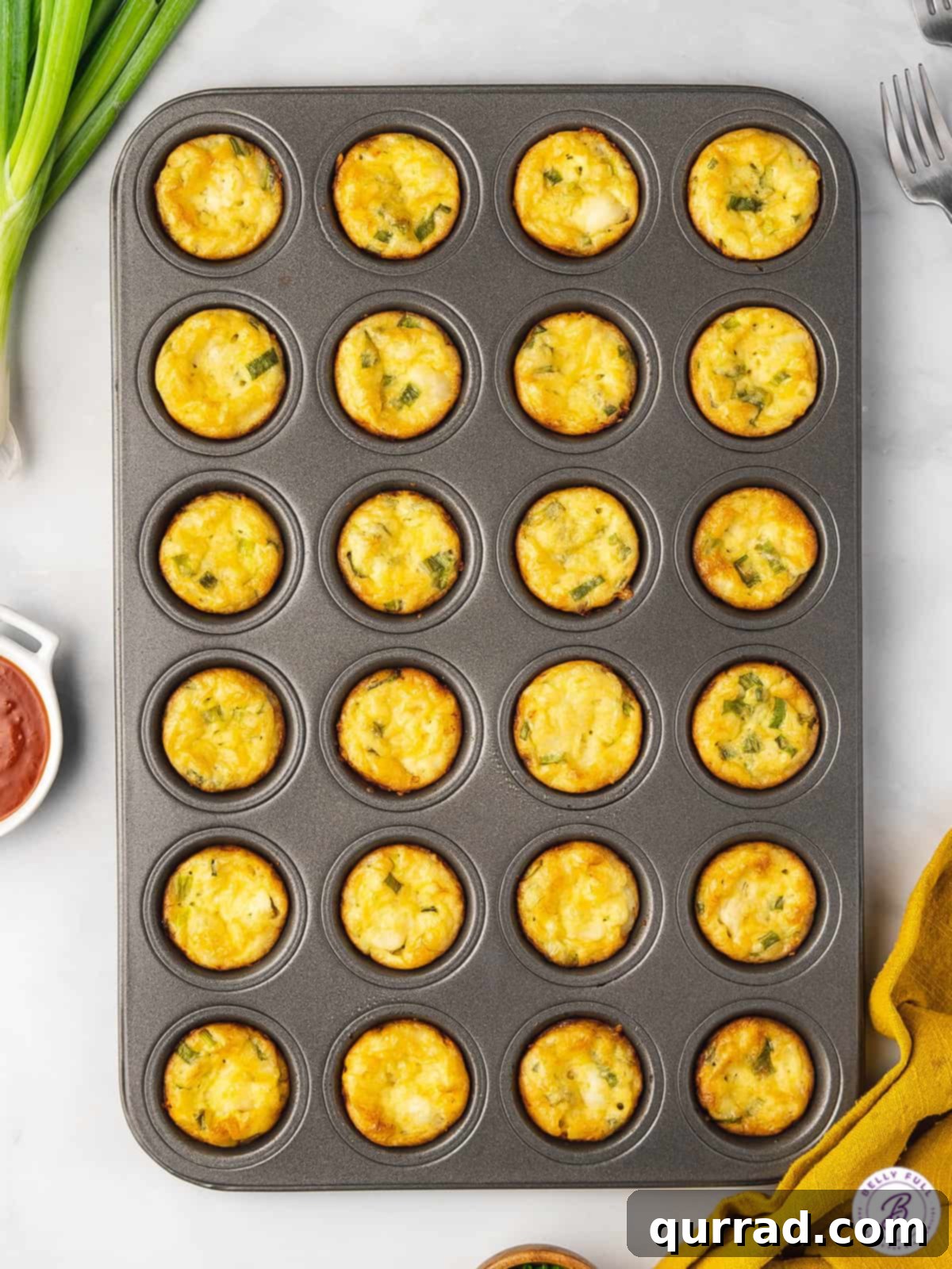 Overhead shot of 24 mini quiches perfectly arranged in a mini muffin tin after baking.