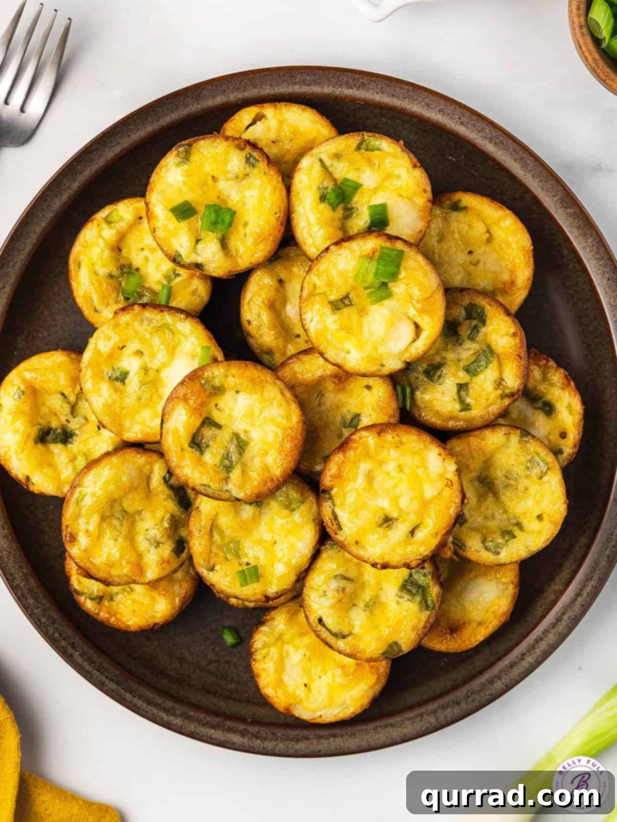 Overhead view of a stack of golden brown crustless crab quiche bites on a plate.