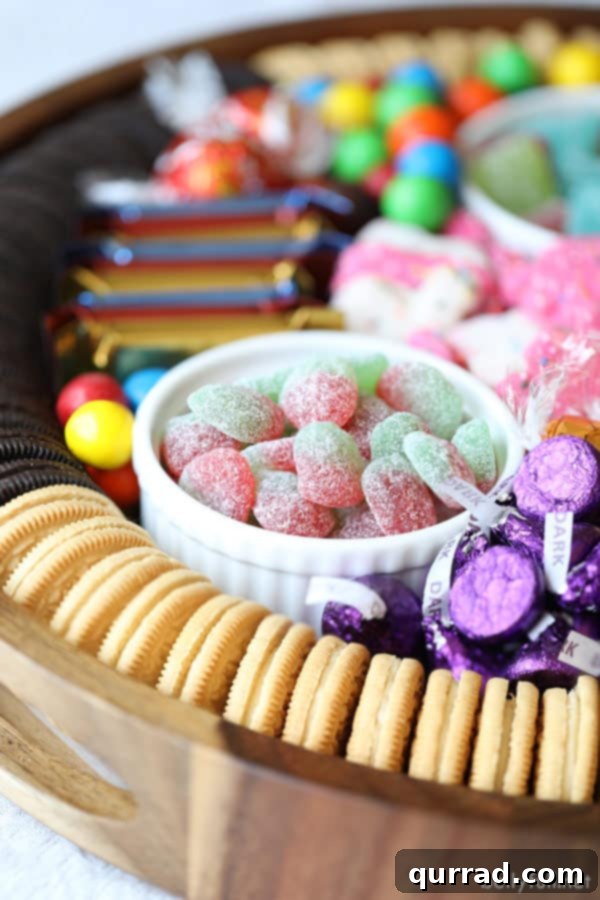 A well-organized Dessert Charcuterie Board with a mix of cookies, chocolates, and gummy candies. Dessert Charcuterie Board featuring Golden Oreos, Hershey's Kisses, and Sour Patch candies arranged artfully