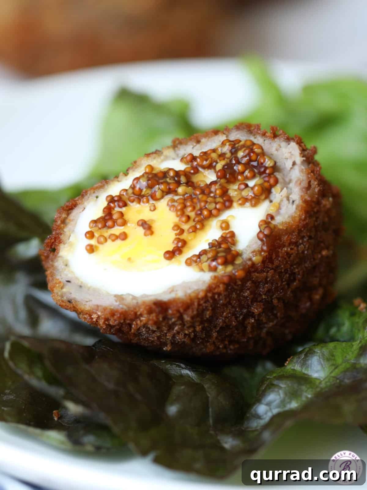 A halved hard-boiled egg, ready to be wrapped in savory sausage for a Scotch Egg. Hard-boiled egg cut in half and topped with mustard seeds, symbolizing a key ingredient