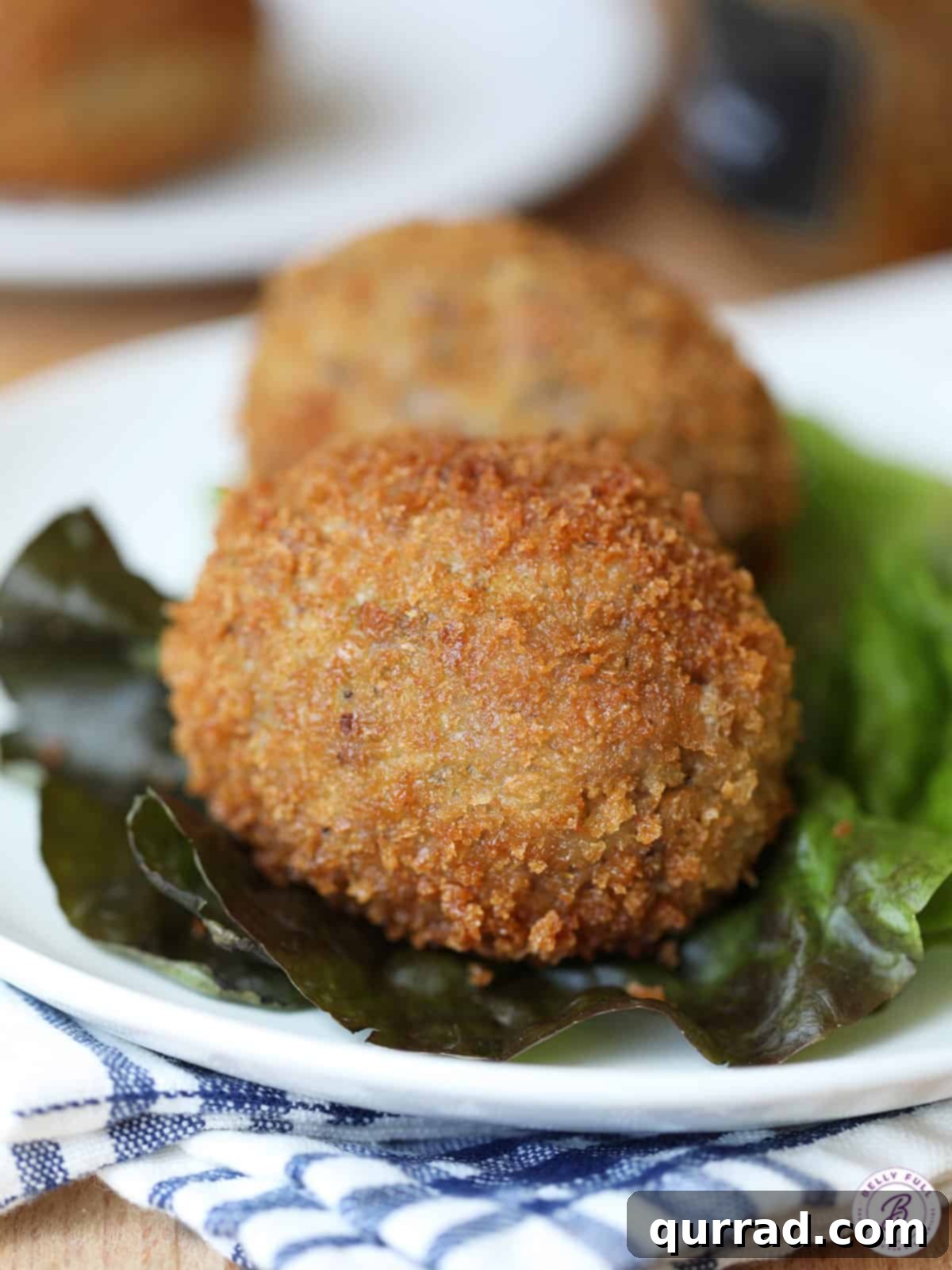 A perfectly cooked whole Scotch Egg, presented on fresh lettuce. Whole Scotch egg sitting on a bed of fresh lettuce leaves, ready to be served