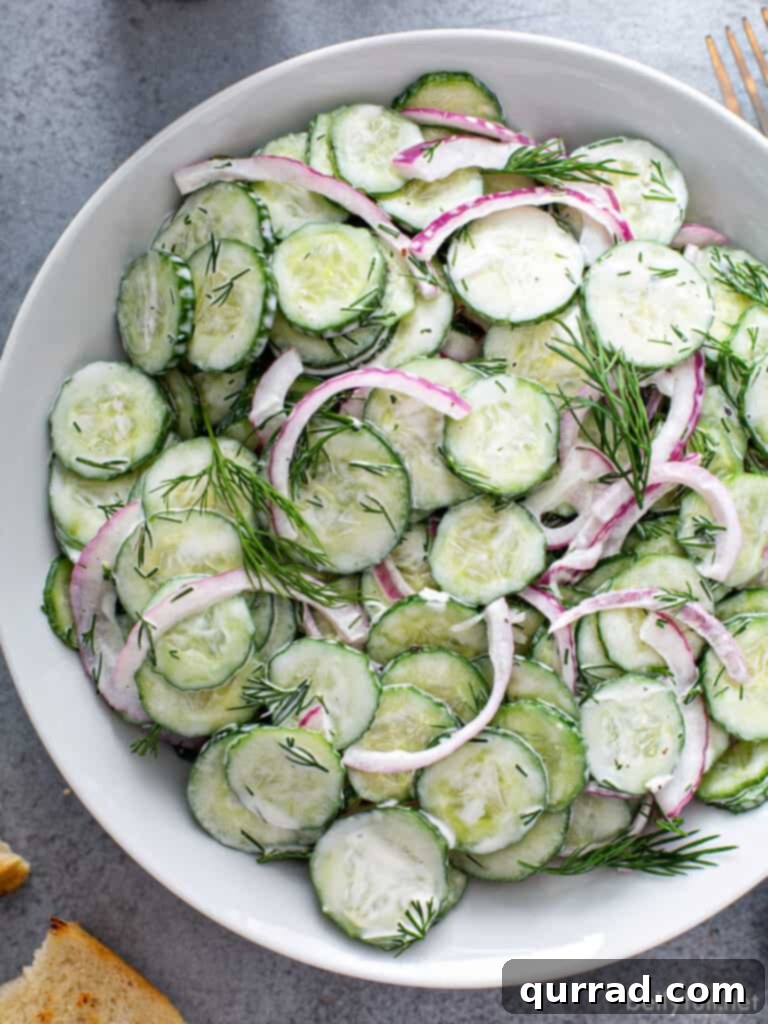 Refreshing Creamy Cucumber Medley 2 Overhead picture of creamy cucumber salad in white serving bowl, garnished with fresh dill.