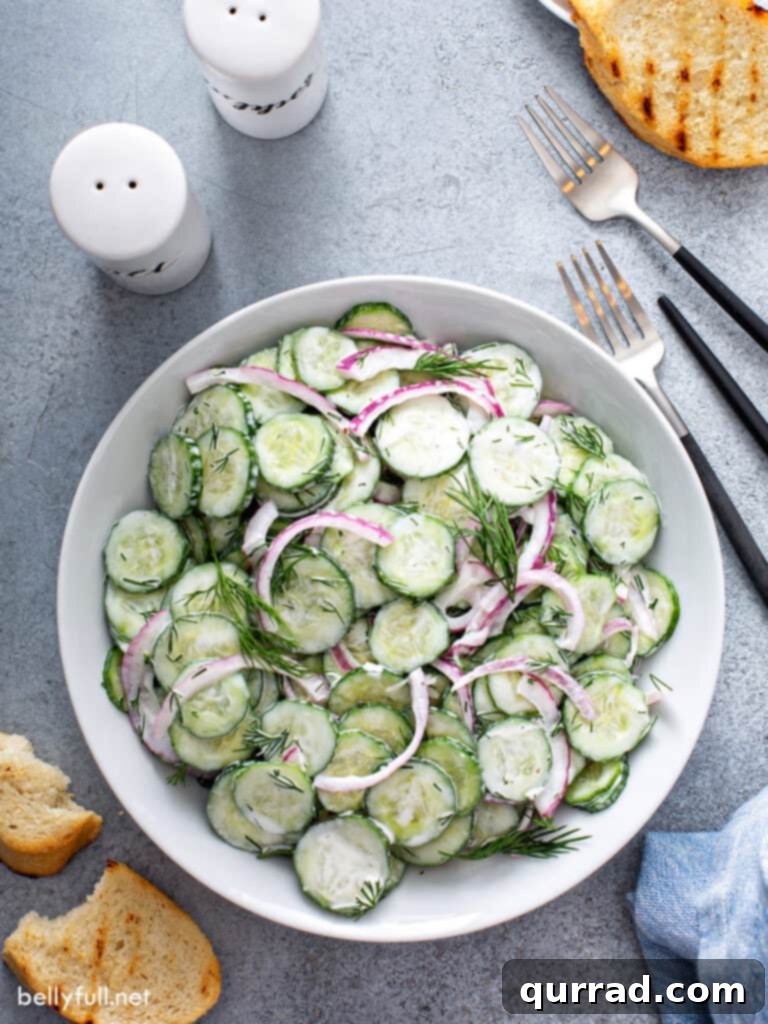 Refreshing Creamy Cucumber Medley 6 Overhead picture of creamy cucumber and onion salad in a white serving dish, ready to eat.
