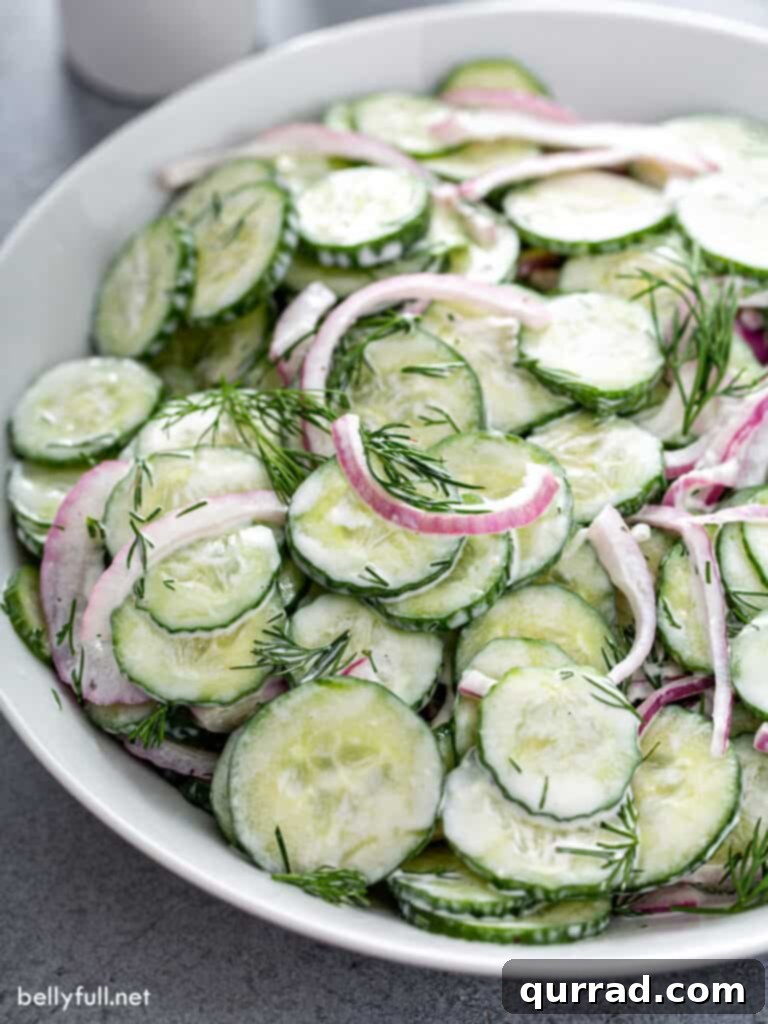 Refreshing Creamy Cucumber Medley 7 Creamy cucumber and onion salad with fresh dill in a serving bowl, ready for a meal.