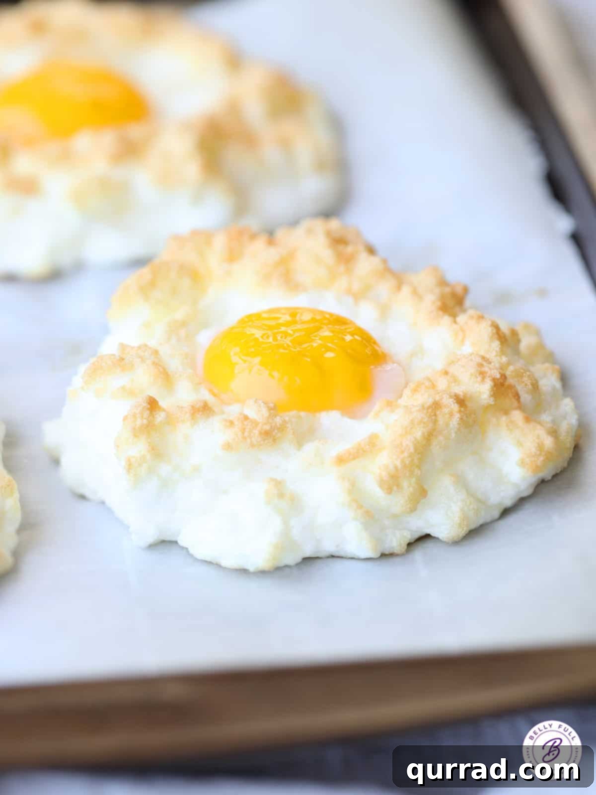 Pillowy Baked Eggs 3 sunnyside-up egg surrounded by baked puffy egg whites, showing the crisp edges and soft interior.