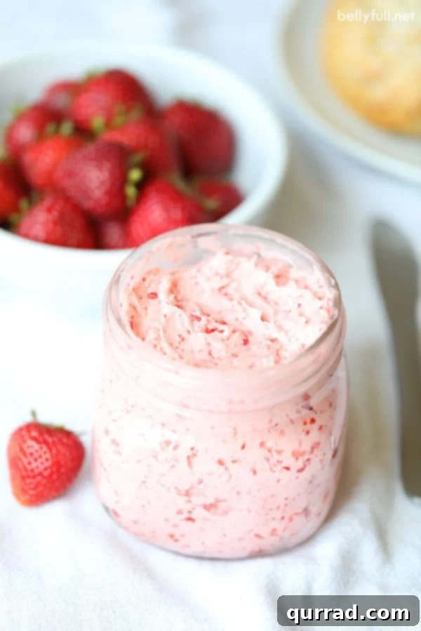 Whipped Strawberry Bliss 3 Strawberry Honey Butter in glass jar with fresh strawberries behind it in white bowl