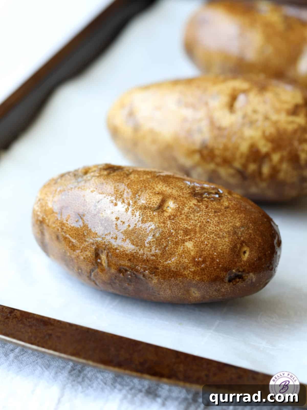 Fluffy Crispy Oven Baked Potatoes 3 oiled russet potatoes on baking sheet