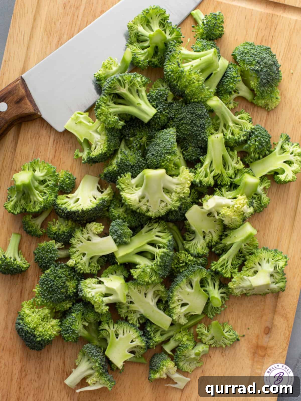 Crispy Roasted Broccoli 3 Pile of fresh, raw broccoli florets on a wooden cutting board, meticulously prepared and ready for seasoning before roasting.