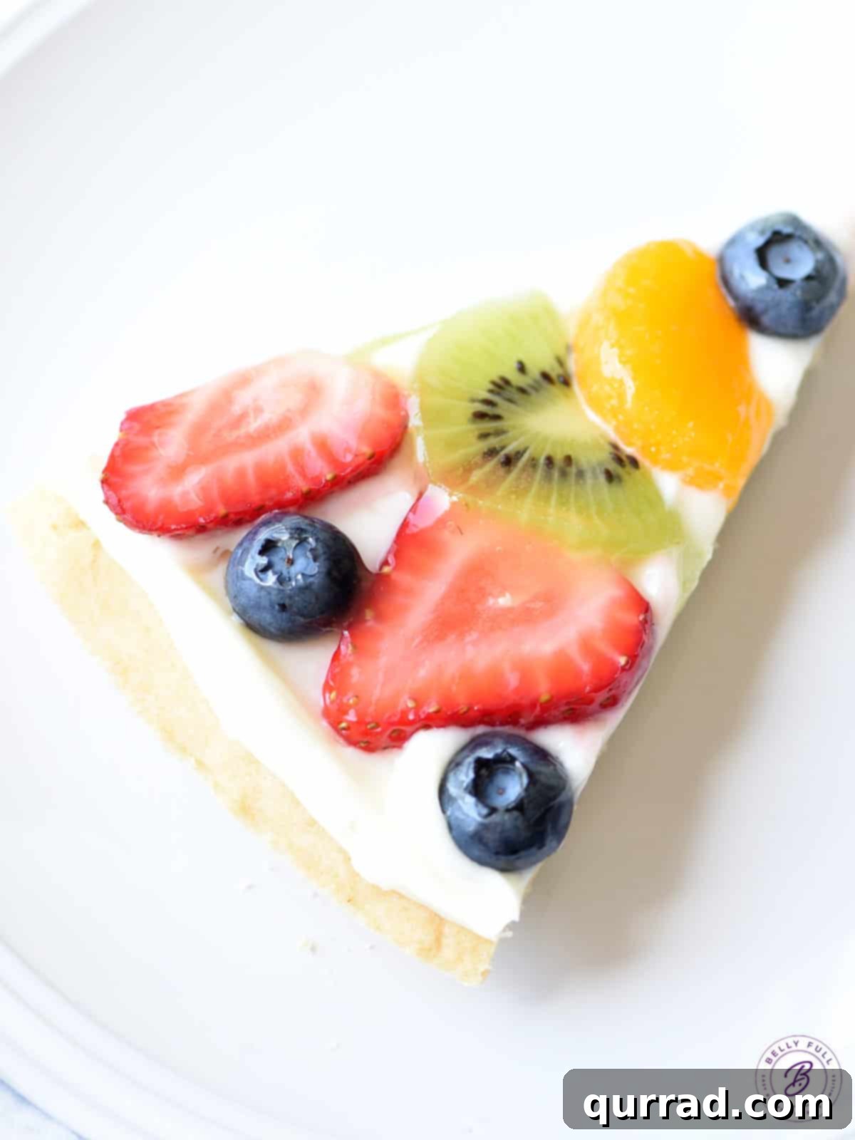 Vibrant Fruit Pizza 10 A slice of Dessert Fruit Pizza, showcasing the sugar cookie crust, cream cheese frosting, and colorful fruit topping with a clear glaze.
