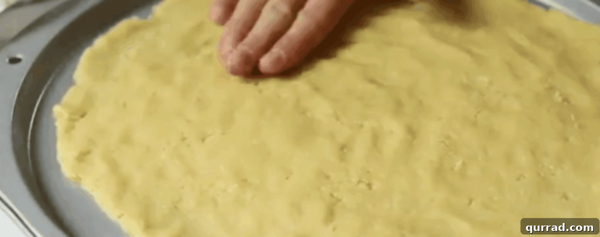 Vibrant Fruit Pizza 6 Pressing chilled sugar cookie dough evenly into a 12-inch pizza pan.