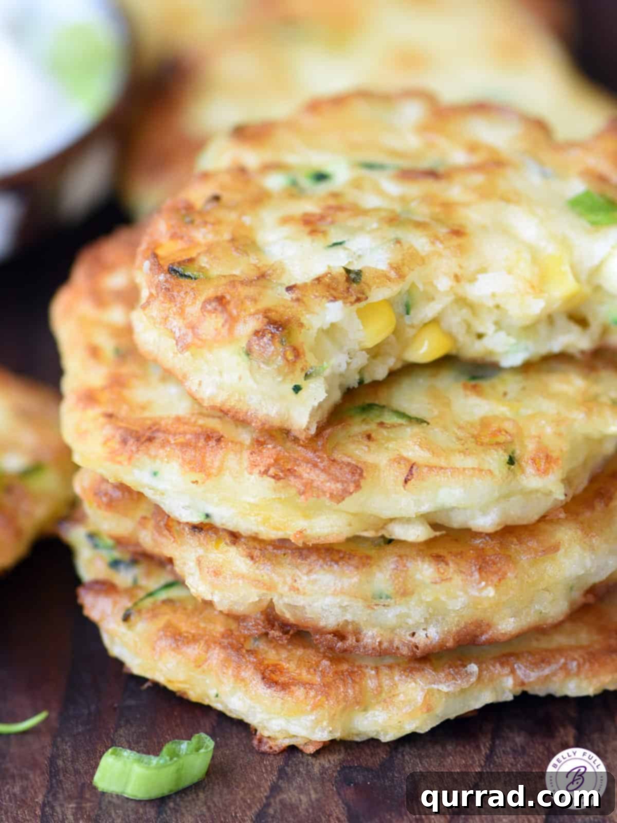 Golden Zucchini and Corn Fritters 3 close-up stack of crispy zucchini corn fritters with a bite taken from the top one