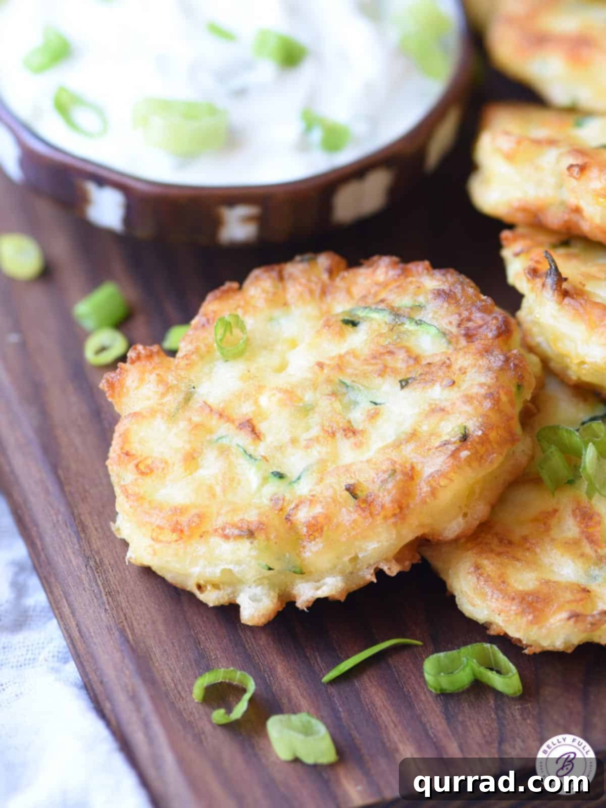 Golden Zucchini and Corn Fritters 4 a single zucchini corn fritter resting on a wooden cutting board
