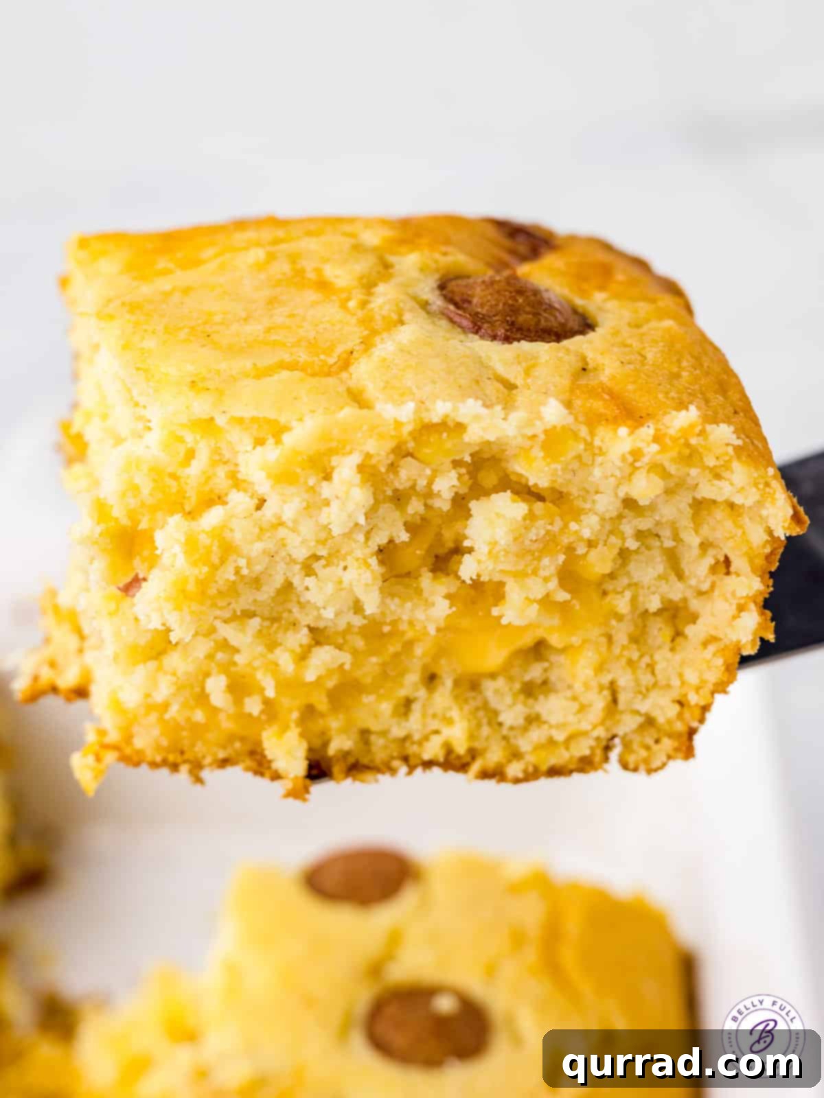 A square piece of Corn Dog Casserole being lifted with a serving spatula, ready to be placed on a plate.