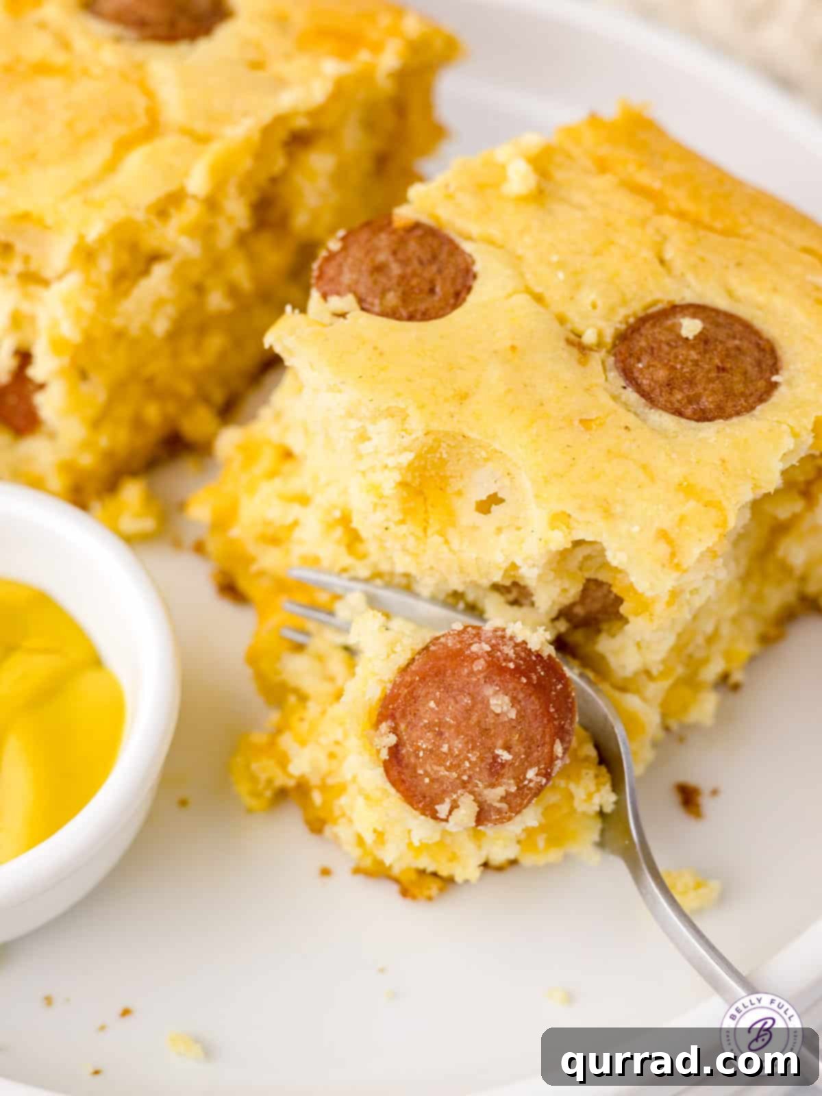 A close-up shot of a bite of Corn Dog Casserole on a fork, showing the texture and ingredients.
