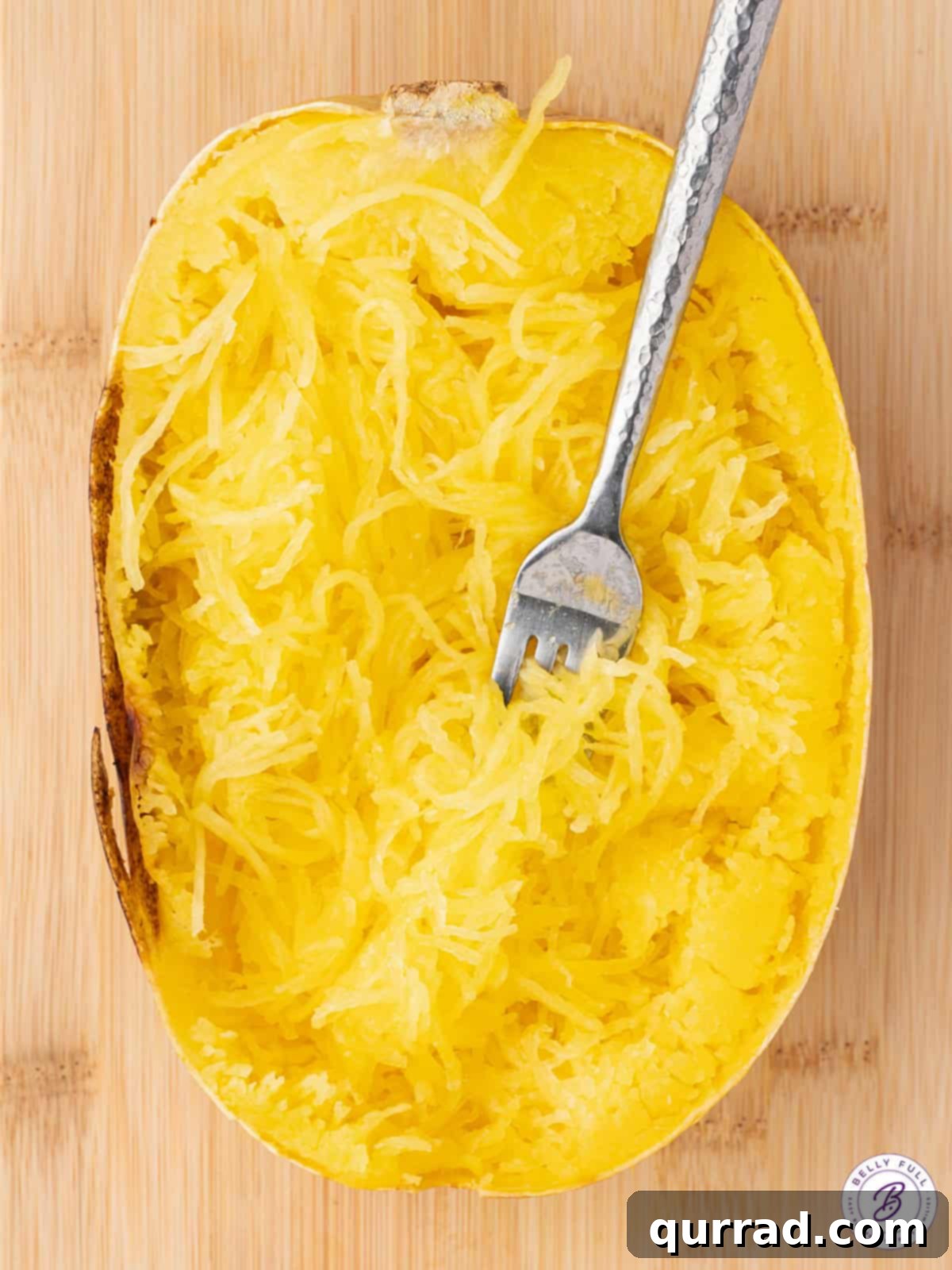 Half of a perfectly roasted spaghetti squash with golden, pulled strands ready to be served
