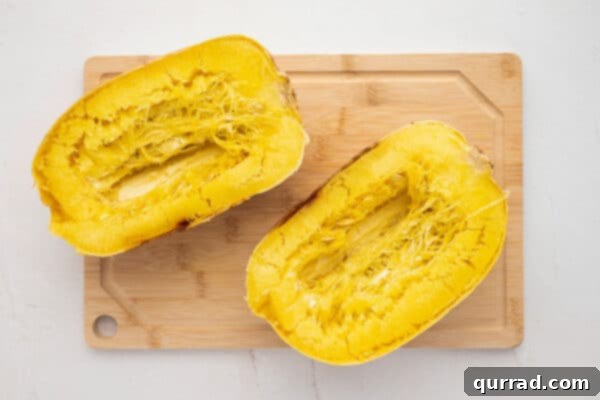 2 roasted spaghetti squash halves on cutting board