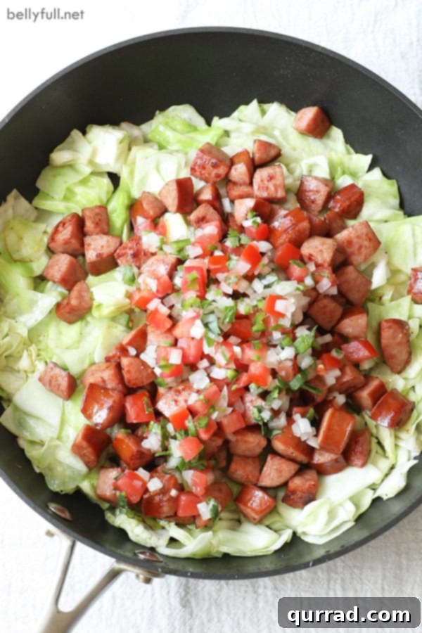 A delicious one-pan Mexican Kielbasa Cabbage Skillet simmering on the stove, perfect for a healthy and quick dinner. Cooking Mexican Kielbasa Cabbage and pico de gallo in a large skillet