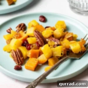 A plate with roasted winter squash and pecans, garnished with herbs.