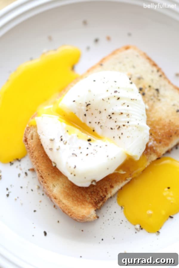 A perfectly cooked poached egg split open to reveal its rich, golden runny yolk