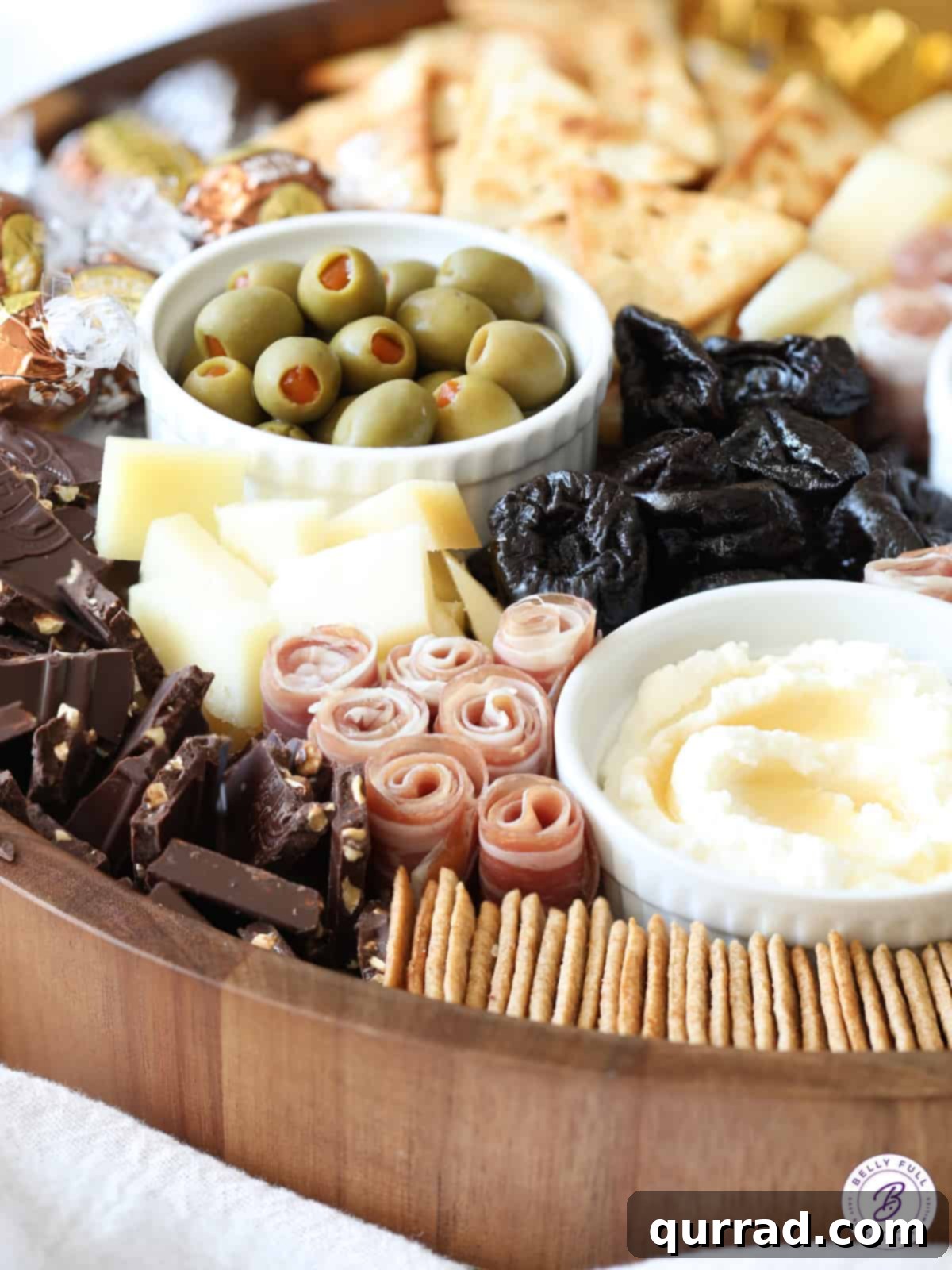 Close-up shot of a rustic snack board, showcasing artfully arranged prosciutto, vibrant green olives, sweet prunes, and a selection of cheeses