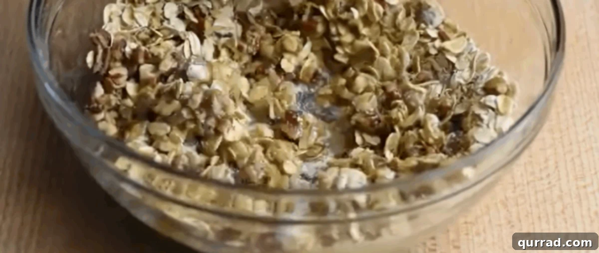 A glass bowl containing old-fashioned oats, all-purpose flour, brown sugar, chopped pecans, and melted butter for the crisp topping.