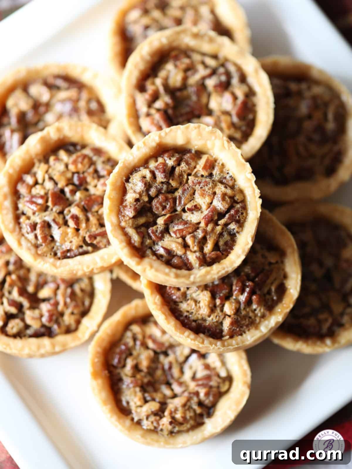 Pecan Pie Bites 3 An overhead shot showcasing a delicious stack of freshly baked mini pecan pies, golden brown and inviting.