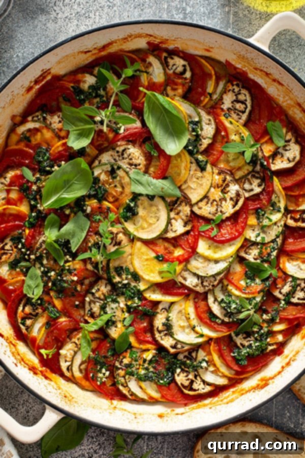 Provencal Ratatouille Delight 2 Overhead view of spiraled Ratatouille in a white baking dish, showcasing vibrant, thinly sliced vegetables