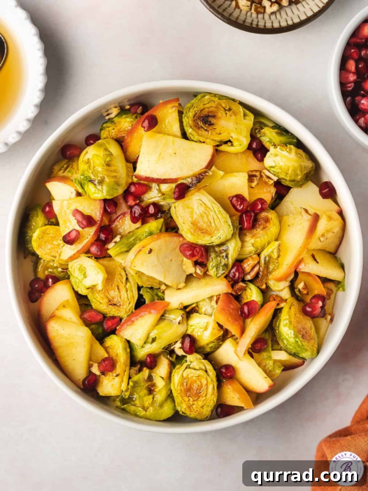 Sweet & Savory Roasted Brussels with Apples 2 Bowl of oven roasted brussels sprouts with apples and pomegranate seeds, ready to serve.