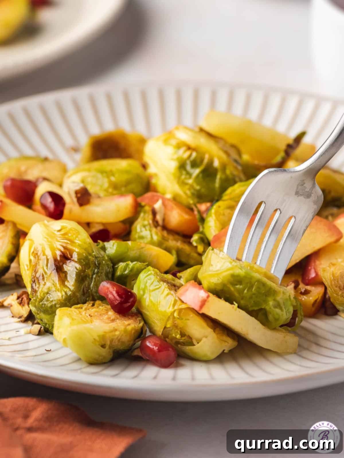 Sweet & Savory Roasted Brussels with Apples 5 A fork holding a cooked halved brussels sprout and a slice of apple, illustrating the texture.
