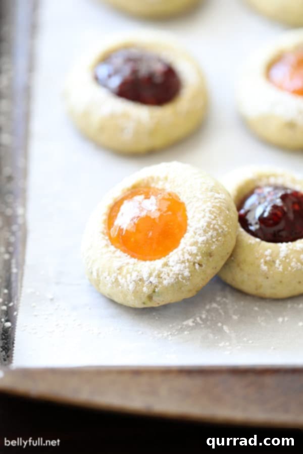 These Thumbprint Cookies are buttery shortbread, filled with your favorite jam and topped with powdered sugar. Perfect for the holidays or anytime! thumbprint cookies filled with apricot jam