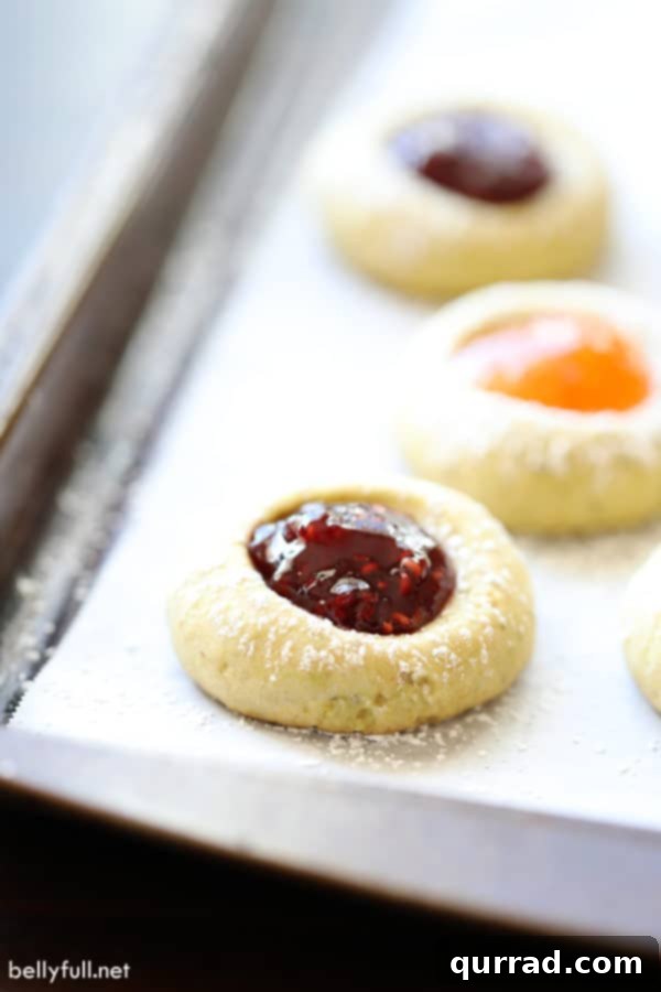 These Thumbprint Cookies are buttery shortbread, filled with your favorite jam and topped with powdered sugar. Perfect for the holidays or anytime! raspberry filled thumbprint cookies