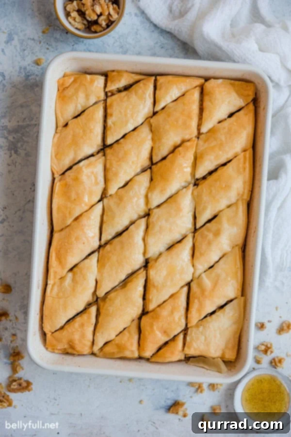 Perfectly cut diamond-shaped Baklava, drenched in syrup and ready to serve. Overhead view of freshly baked Baklava, cut into elegant diamond patterns and glistening with honey syrup, presented in a baking dish.
