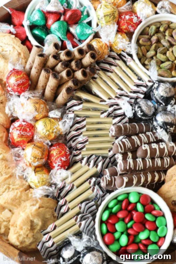A chocolate dessert tray elegantly arranged with an assortment of truffles, M&Ms, Hershey's Kisses, peppermint bark squares, and crisp Pirouline wafers
