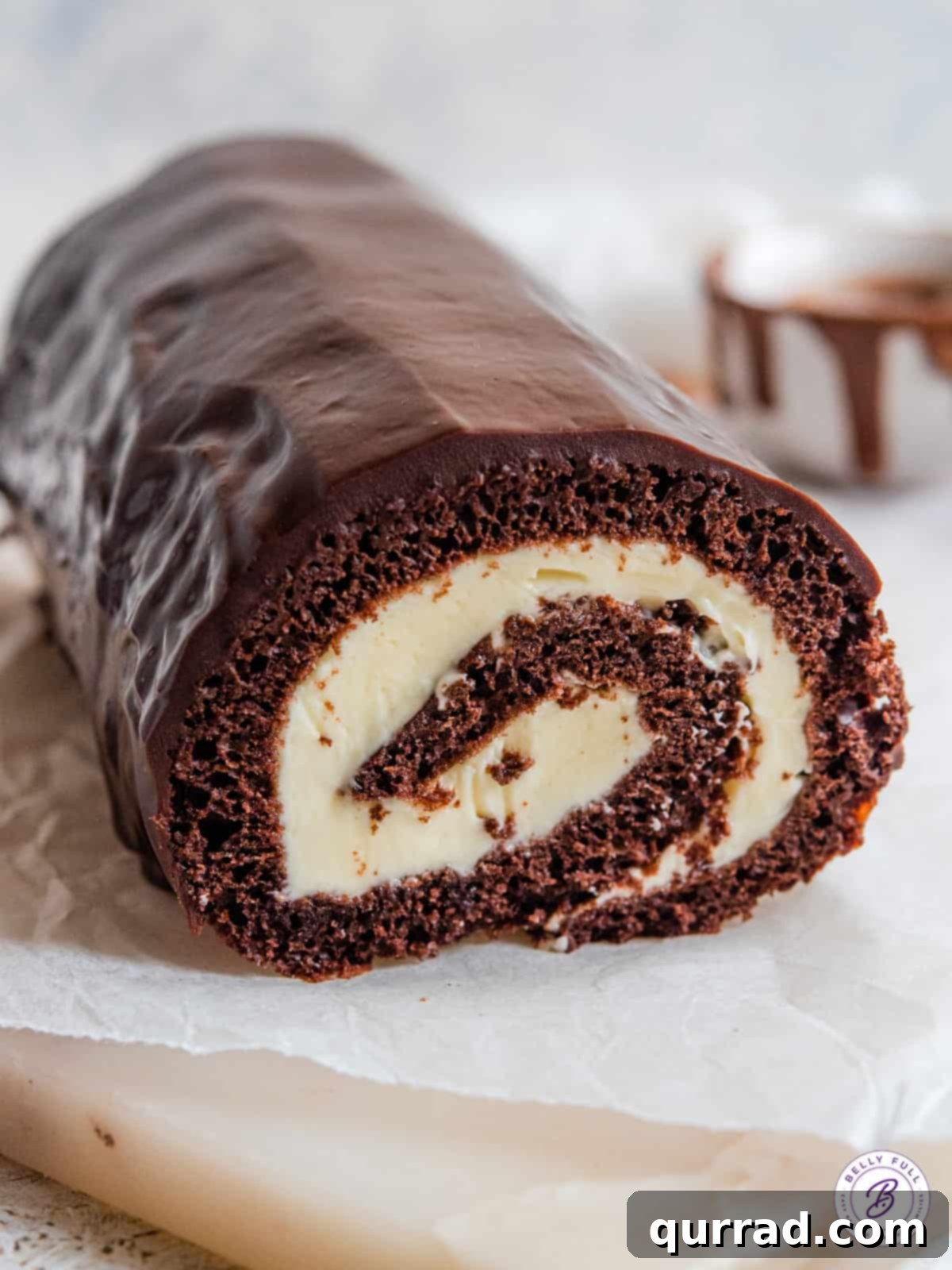 This easy Chocolate Swiss Roll Cake has a light sponge, creamy filling, and coated with a silky ganache. Close up of chocolate Swiss roll.