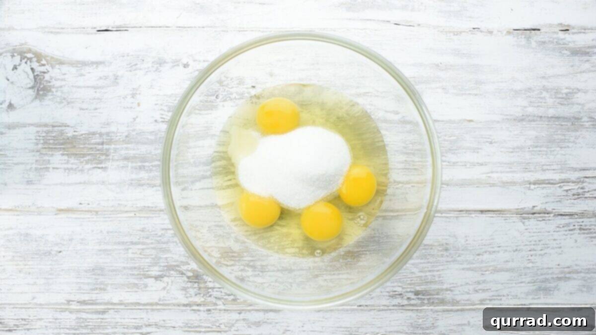 Decadent Chocolate Log 4 Combining eggs and sugar in a glass bowl.