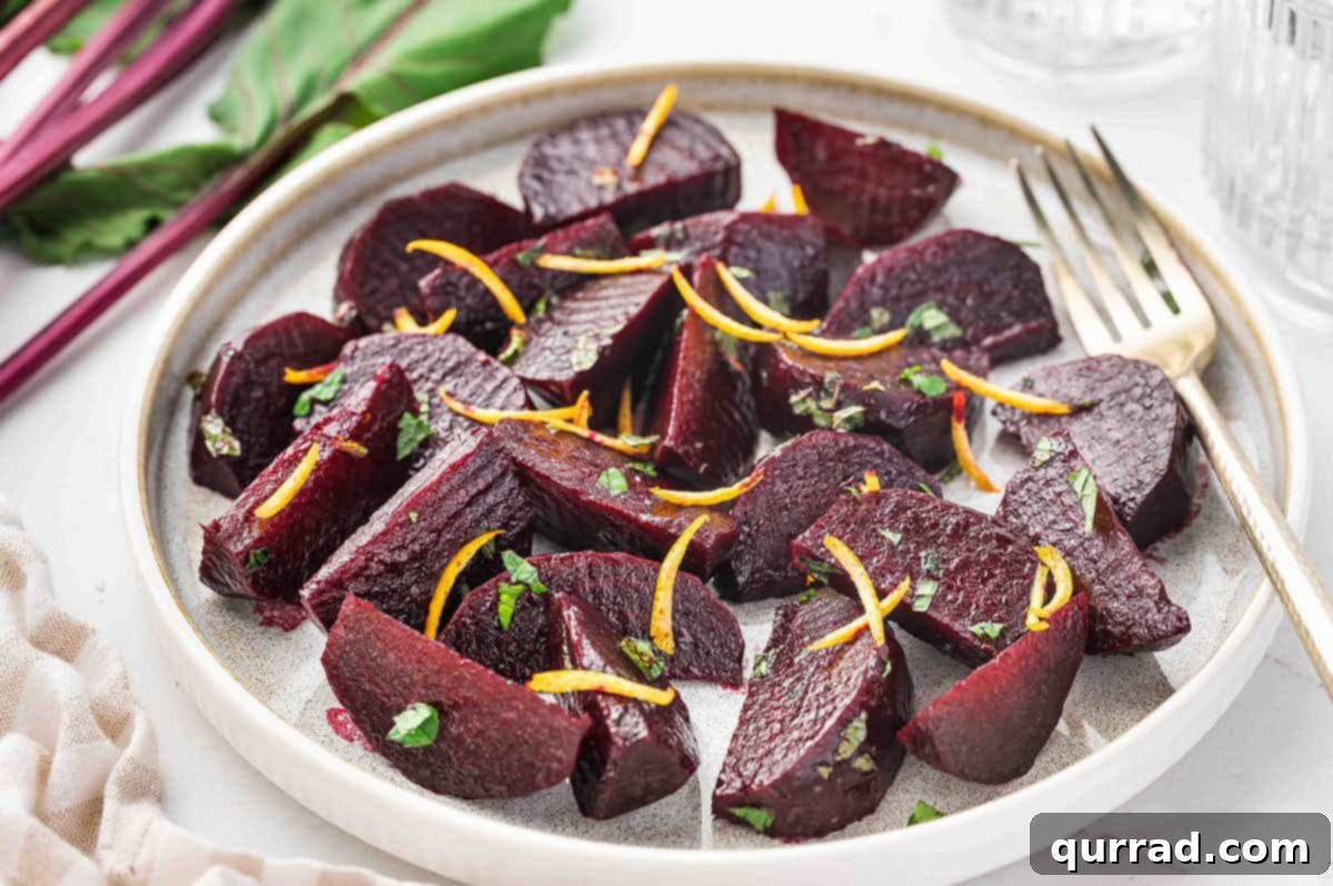 Wedges of perfectly roasted beets, beautifully arranged and garnished with fresh orange peel and parsley on a white plate