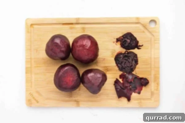 4 peeled roasted beets on a cutting board, ready for slicing or dicing