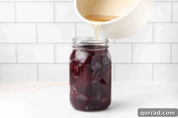 Brine being poured over sliced beets in a jar