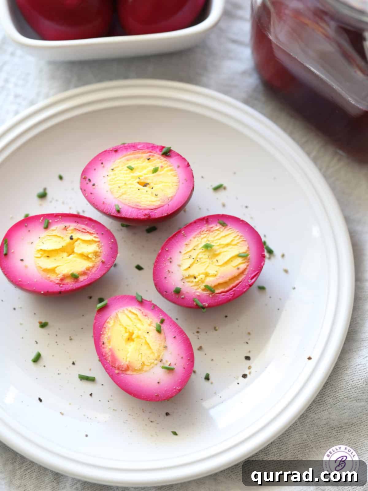 Ruby Red Pickled Eggs 5 overhead plate of 4 hard boiled egg halves dyed pink with chives and pepper