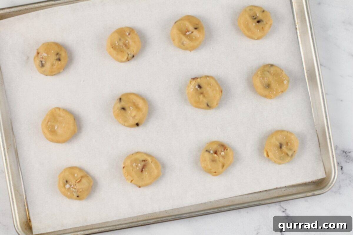 Kitchen sink cookie dough balls on a lined baking sheet. 