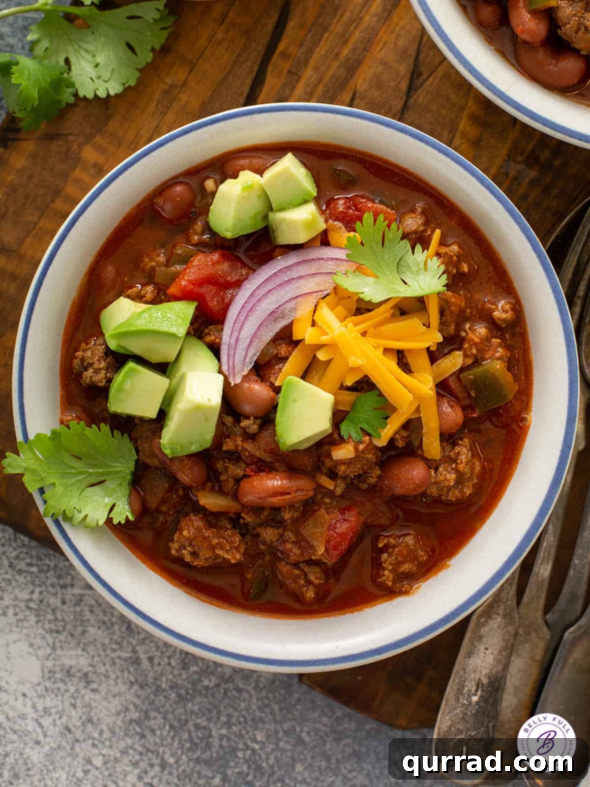 overhead bowl of chili with shredded cheese and avocado cubes