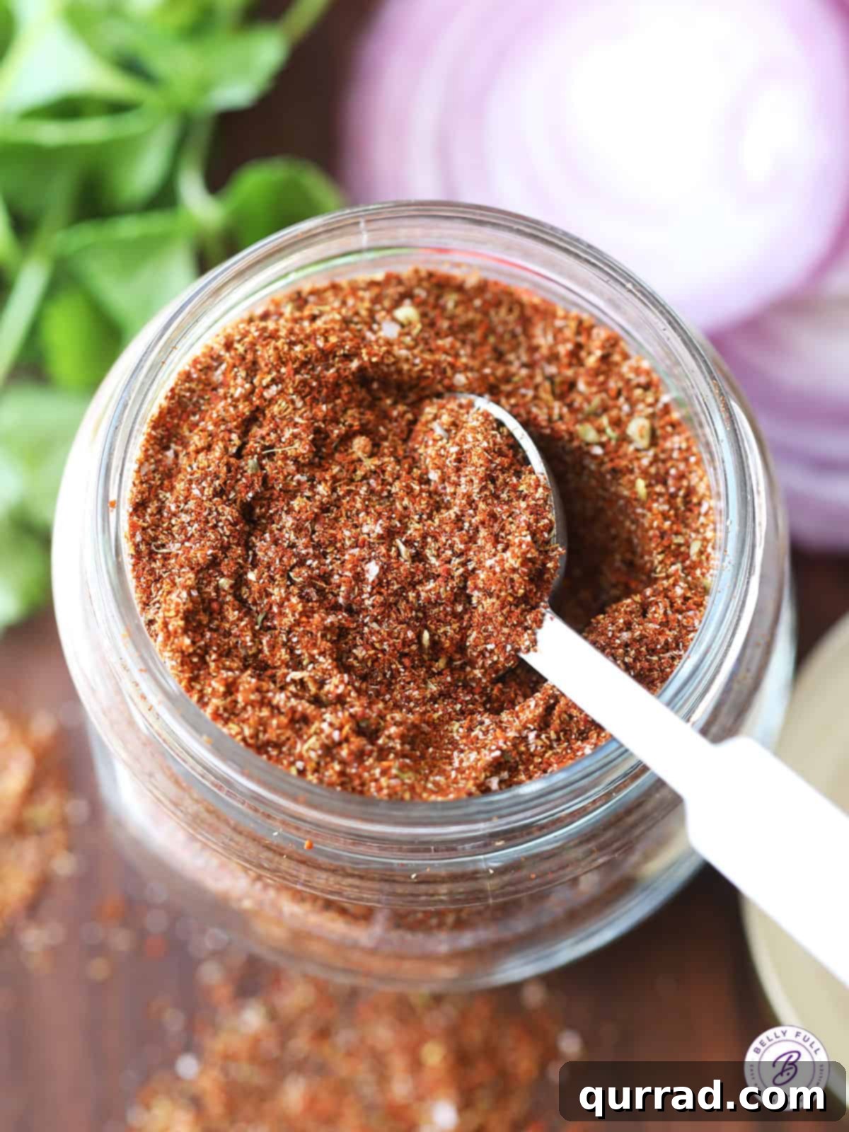 Craft Your Perfect Taco Spice Blend 4 An overhead view of a scoop of homemade taco seasoning inside a glass jar, highlighting its rich color and texture.