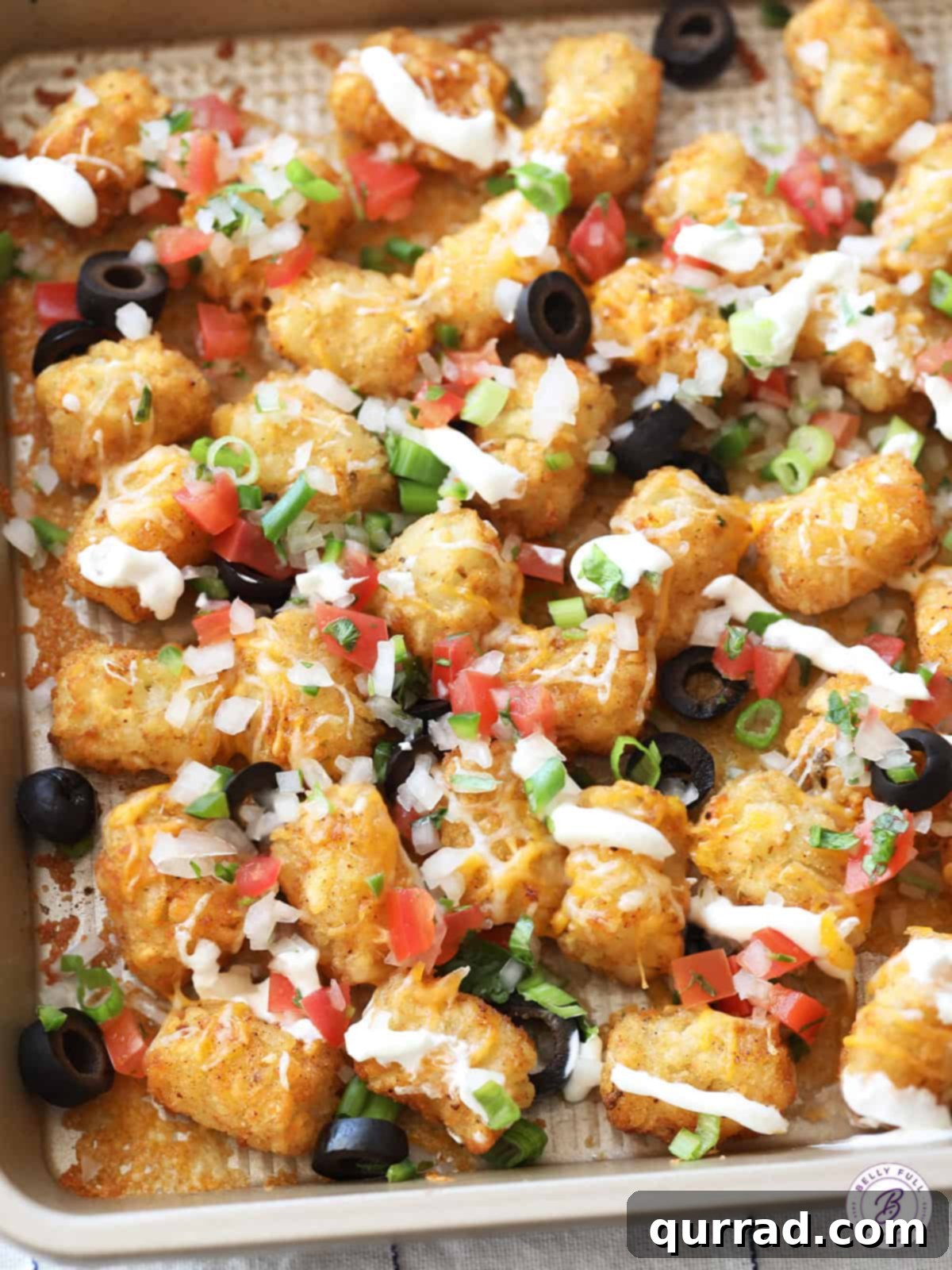 Spud Nacho Supreme 2 Overhead view of Cheesy Totchos, Tater Tot Nachos on a sheet pan, loaded with toppings.
