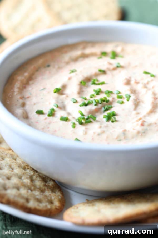 Close-up of creamy veggie dip in a white bowl, garnished with freshly diced chives, showcasing its smooth texture and inviting green flecks.